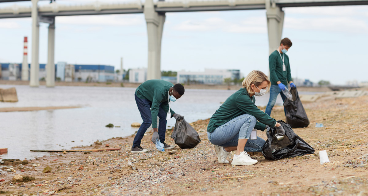 Group of volunteers picking cleaning up a river bank